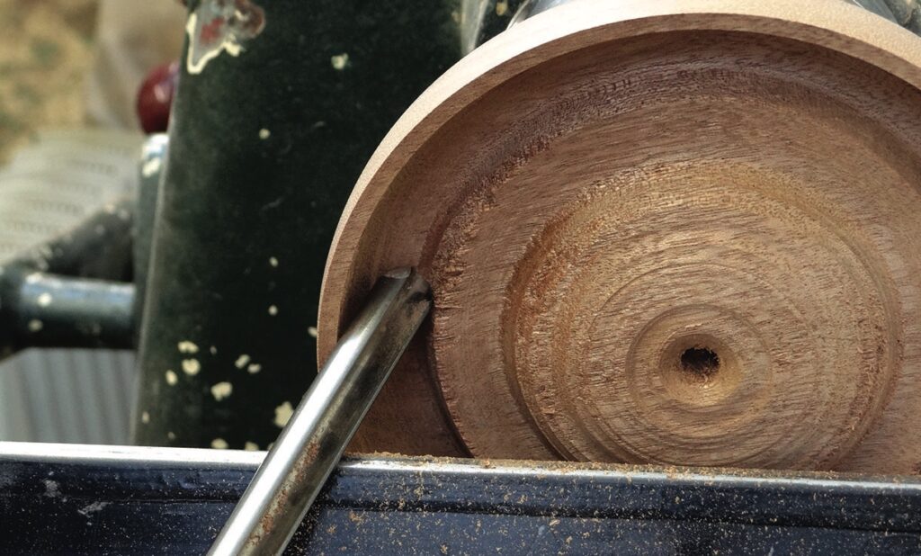 Chisel carving wood on a lathe machine.