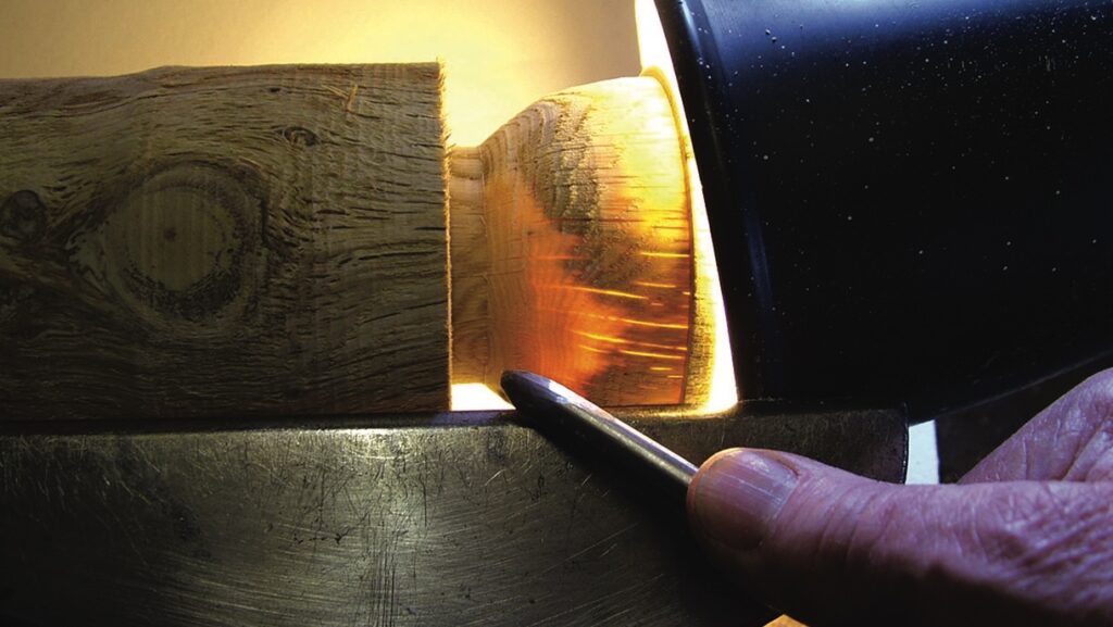 Person woodturning on a lathe with spotlight.