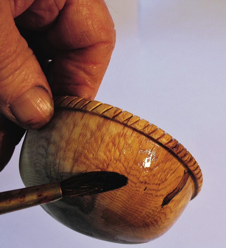 Hand painting decorative wooden bowl with brush.