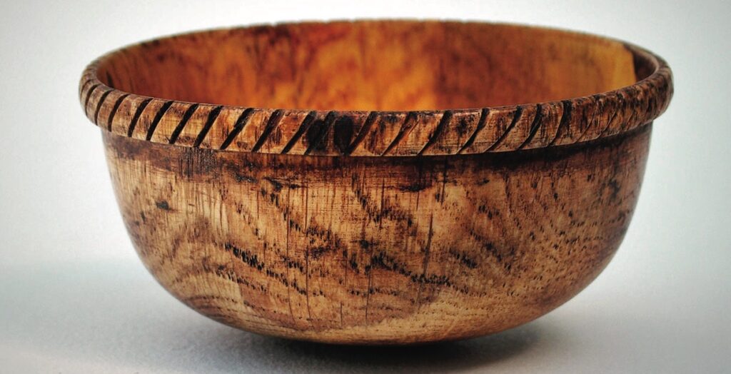 Handcrafted wooden bowl with carved rim design.