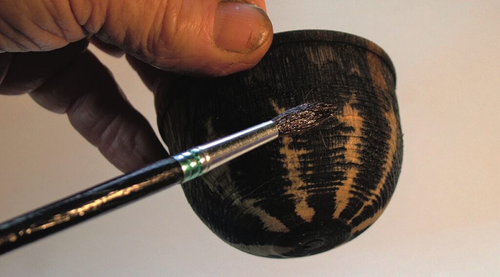Painting wooden bowl with brush in hand