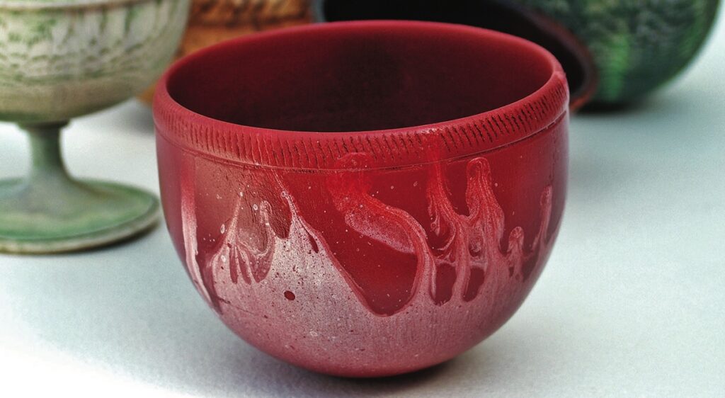 Red ceramic cup with artistic glaze design.