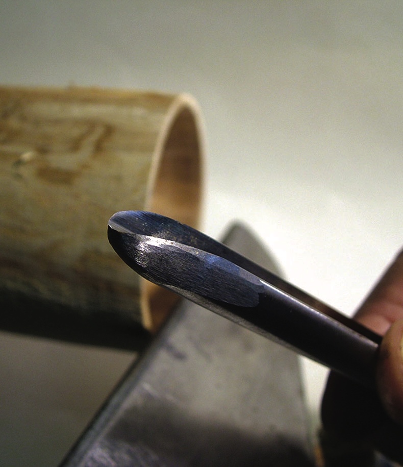 Close-up of sharp woodworking gouge tool and wood.