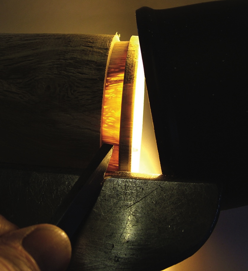 Woodturning lathe illuminating shell-shaped wood slice.