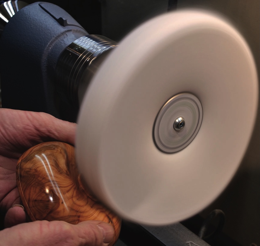 Hand polishing wooden object on a lathe.