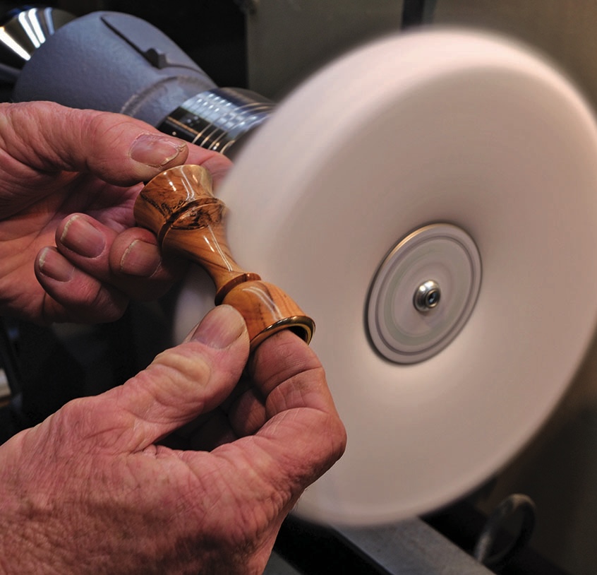 Polishing wooden spindle on a lathe machine.