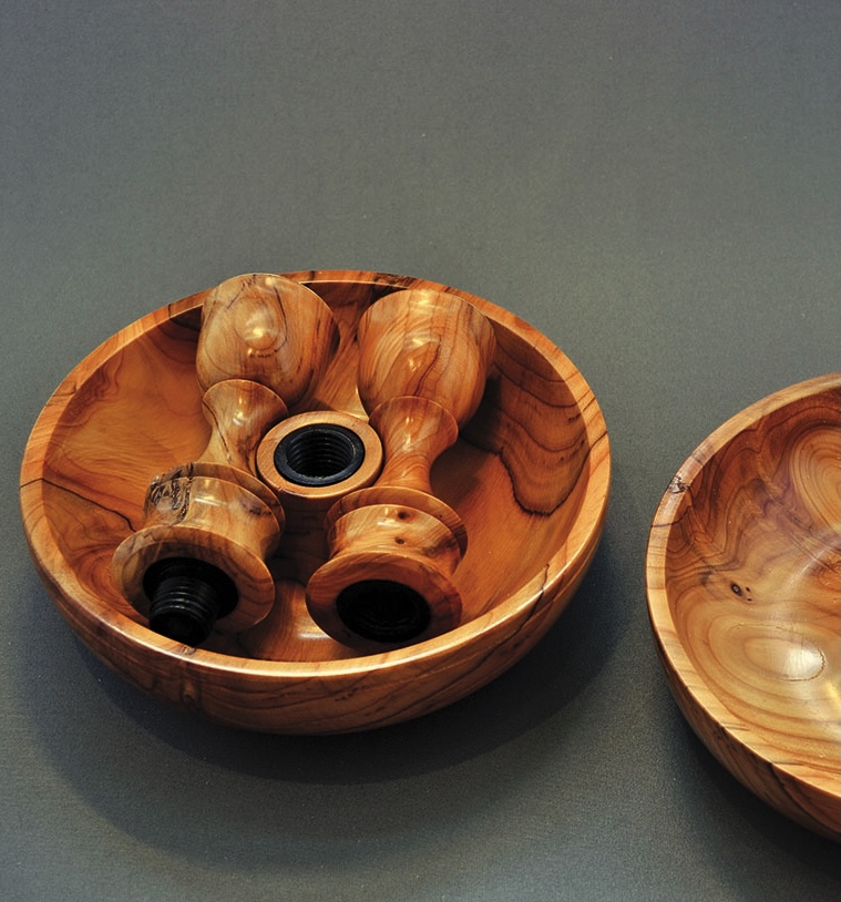 Wooden candlestick holders in a round wooden tray.