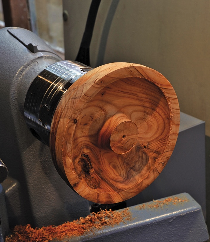 Wood turning on lathe with shavings around.