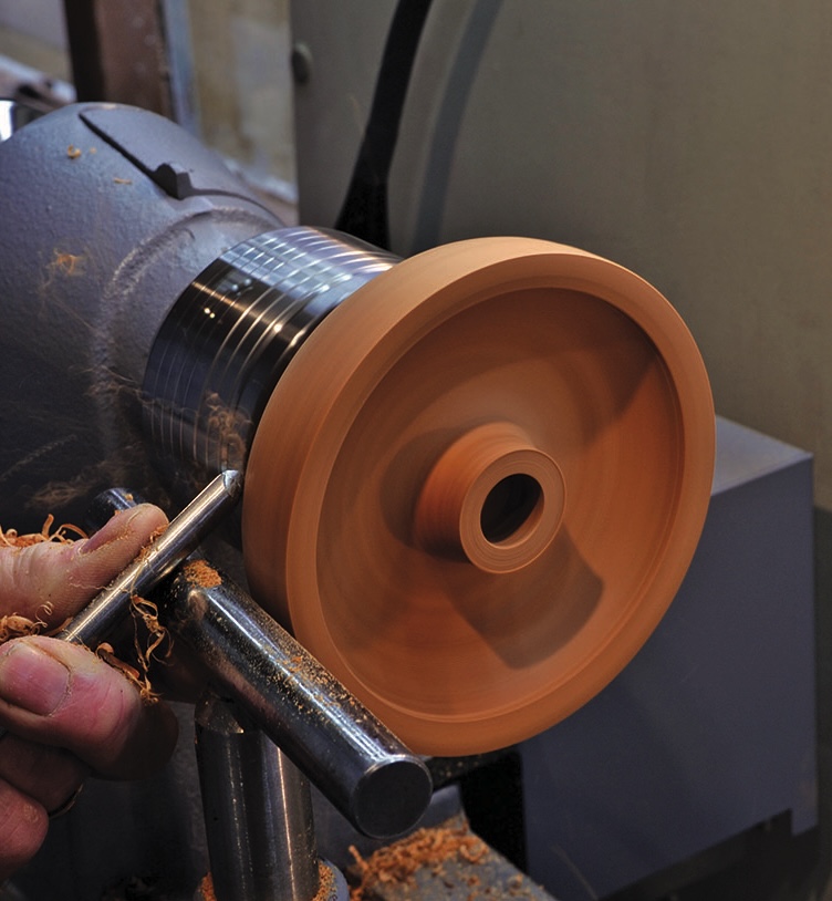 Woodturning process with tool, creating wooden bowl