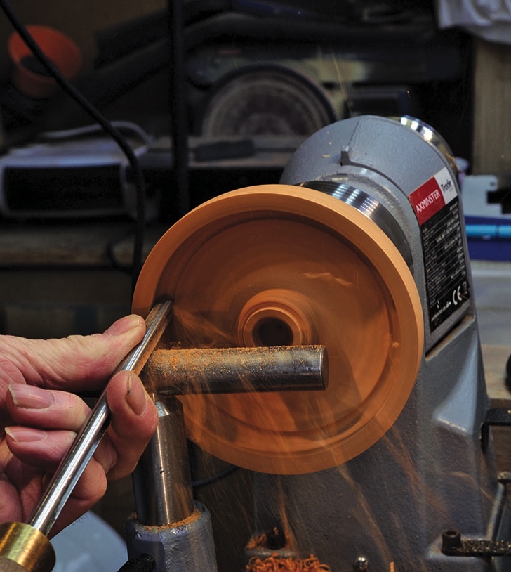 Person carving wood on a lathe machine.