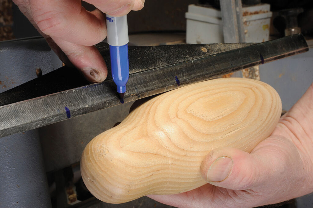 Hand marking wooden piece with blue pen.