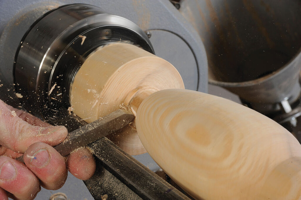 Woodturning on a lathe, creating wooden object.
