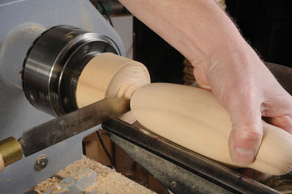 Hand shaping wood on a lathe machine.