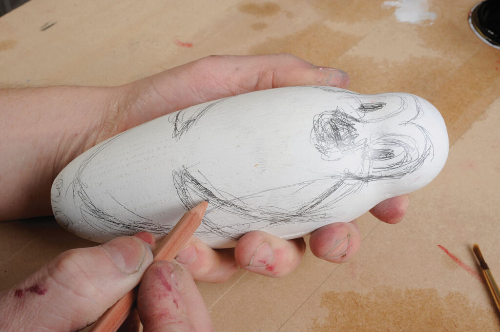 Person sketching on wood with pencil