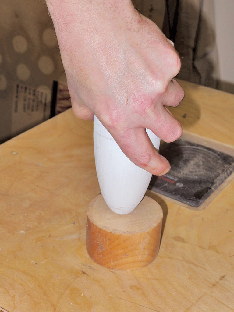 Hand shaping wood with a tool in workshop.