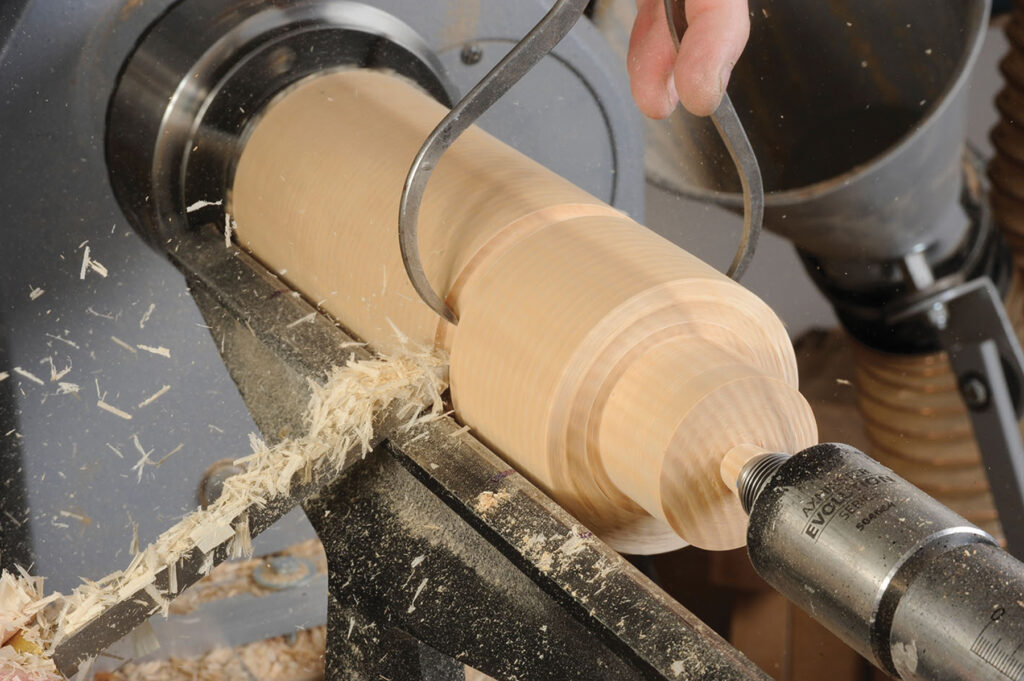 Woodturning tool shaping wooden spindle on lathe.