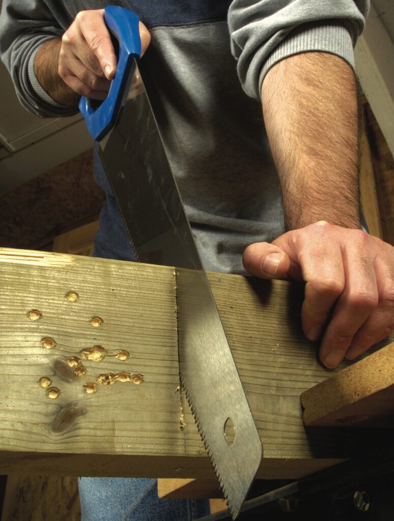 Man sawing wooden plank in workshop.