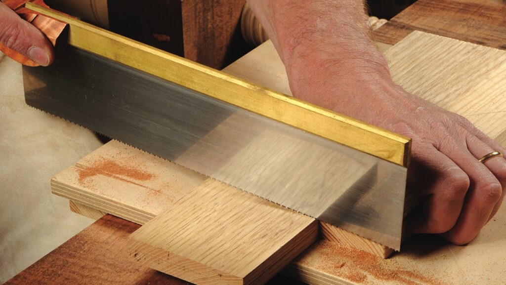 Person cutting wood with a handsaw.