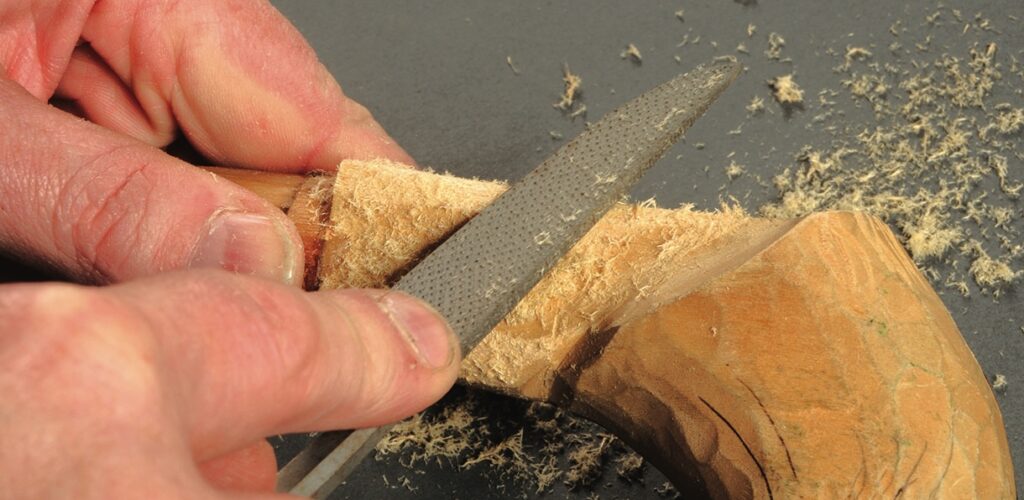 Hands using rasp to shape wood