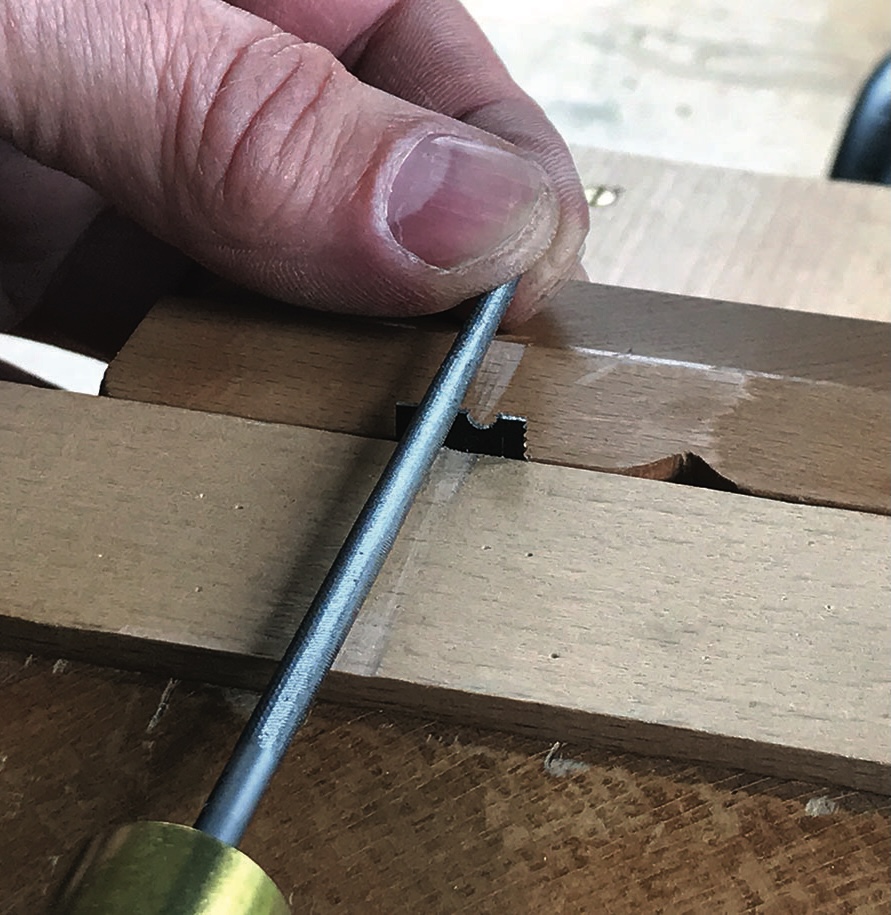 Hand using file on wooden dovetail joint