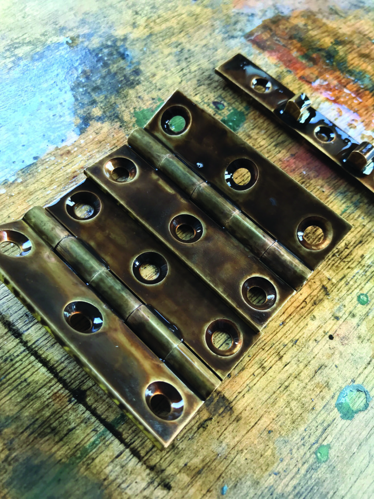 Bronze door hinges on wooden surface.