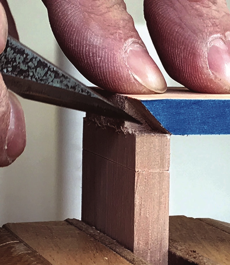 Hands using chisel to carve wood joint precisely.