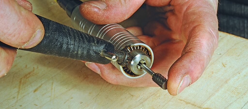 Person using rotary tool on wooden surface.