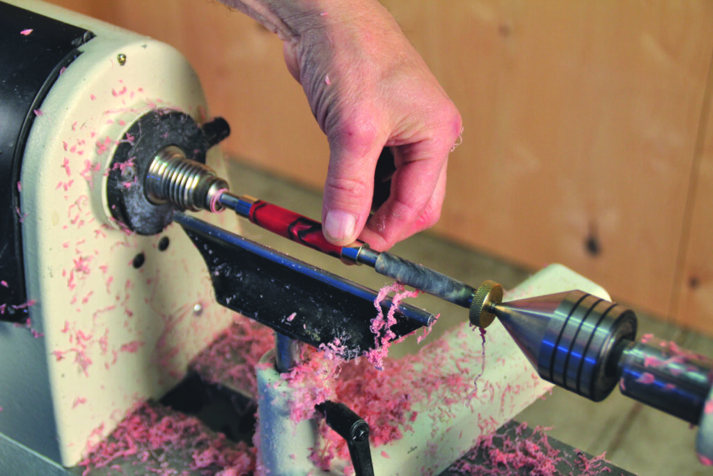 Hand using lathe to shape pen blank