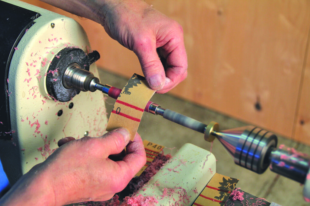 Sanding wood on a lathe with sandpaper.