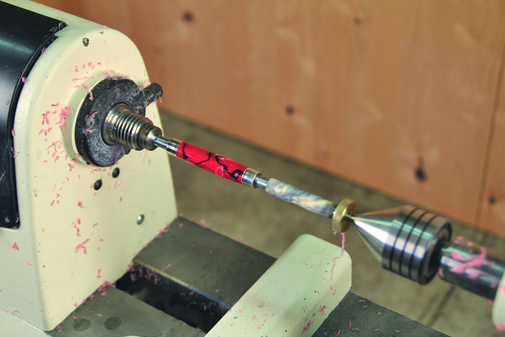 Pen turning on a lathe with wood shavings.