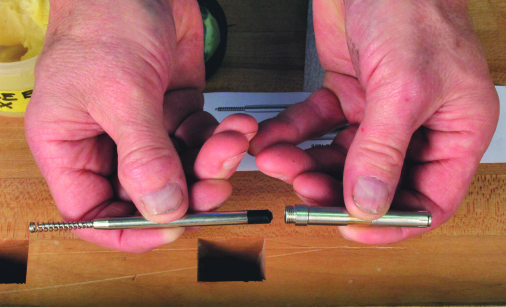 Hands assembling furniture fitting on wooden surface.