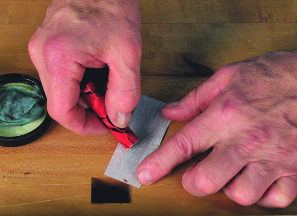 Sharpening a red pencil with sandpaper and paste.