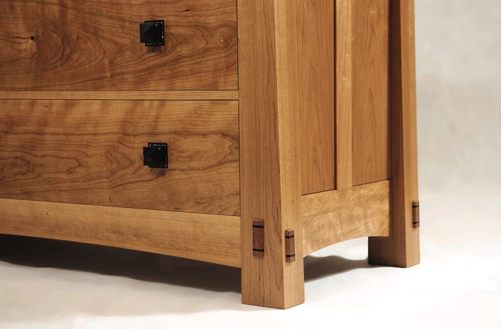 Wooden dresser with black knobs and drawer joints.