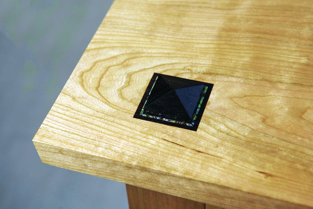 Wooden table corner with decorative black inlay