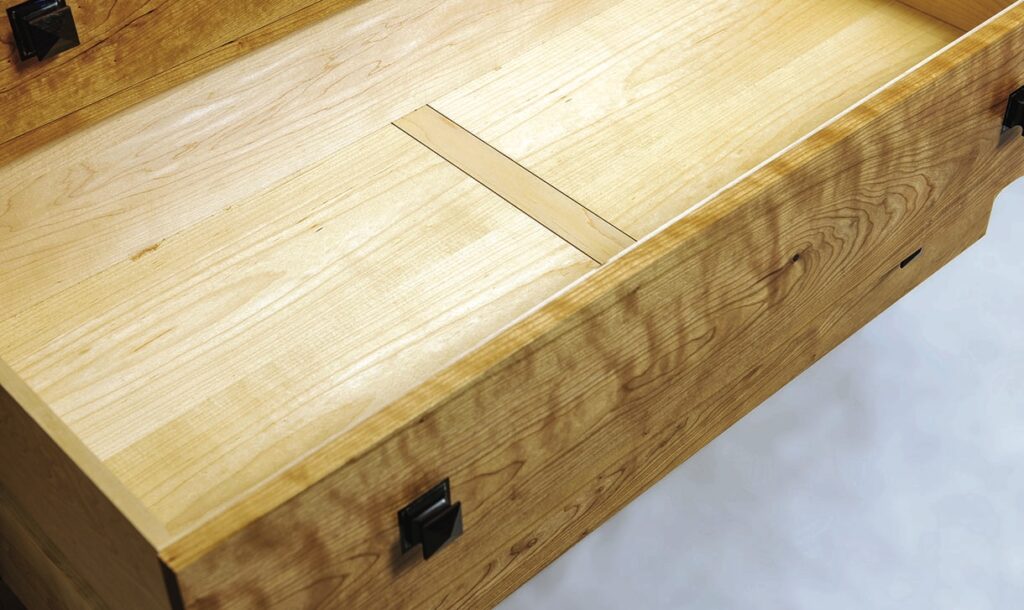 Open wooden drawer with black handles
