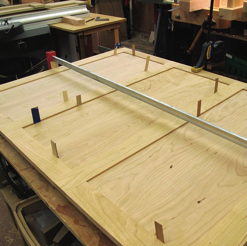 Woodworking process with clamps and wooden panel.
