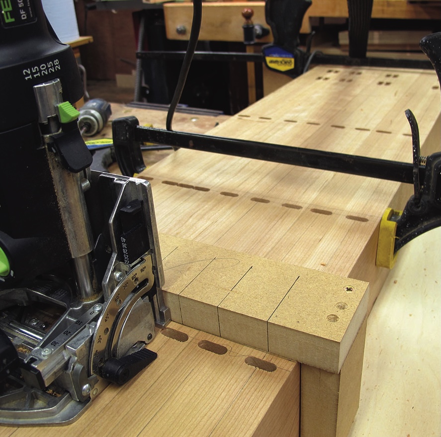 Router creating dovetail joints in wood board.