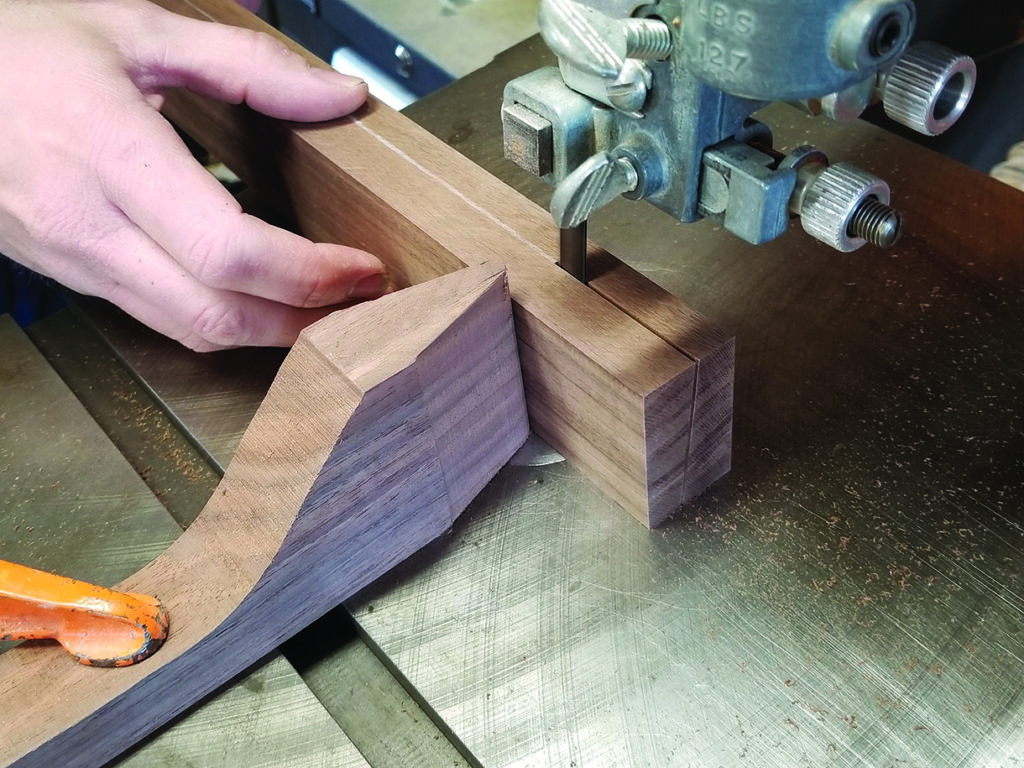 Woodworker using bandsaw to cut wooden piece.