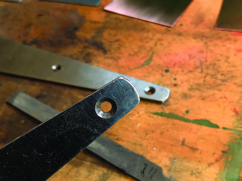 Close-up of metal with hole on workbench.