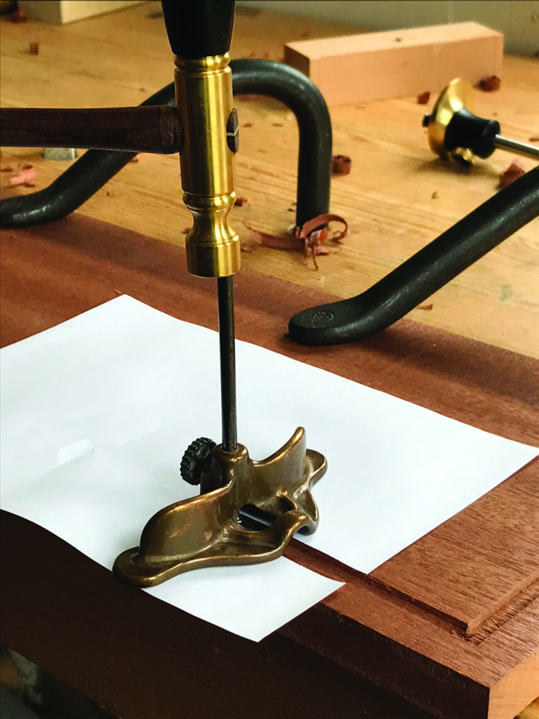Hand-operated drill on wooden surface, close-up view.