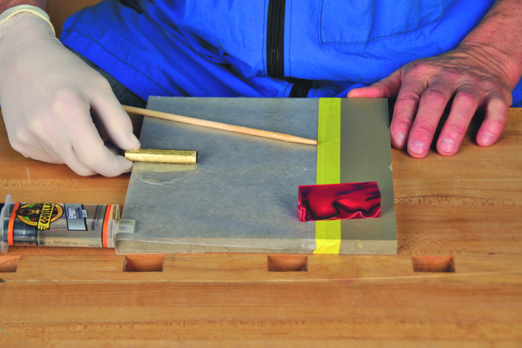Applying adhesive to pen kit on table.