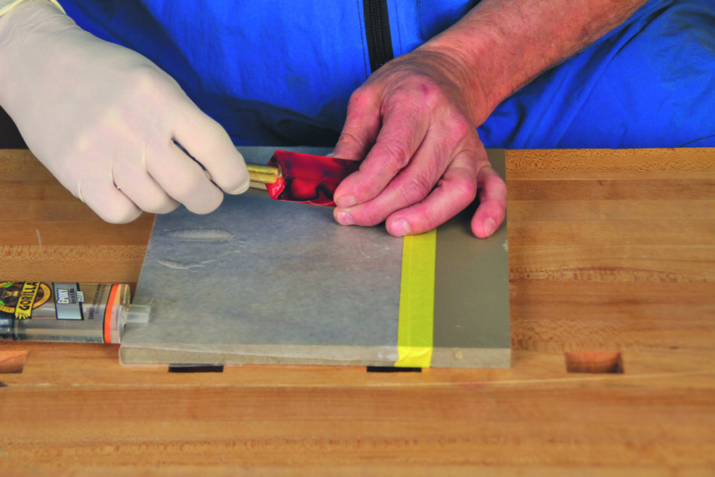Applying adhesive with spatula on workbench.