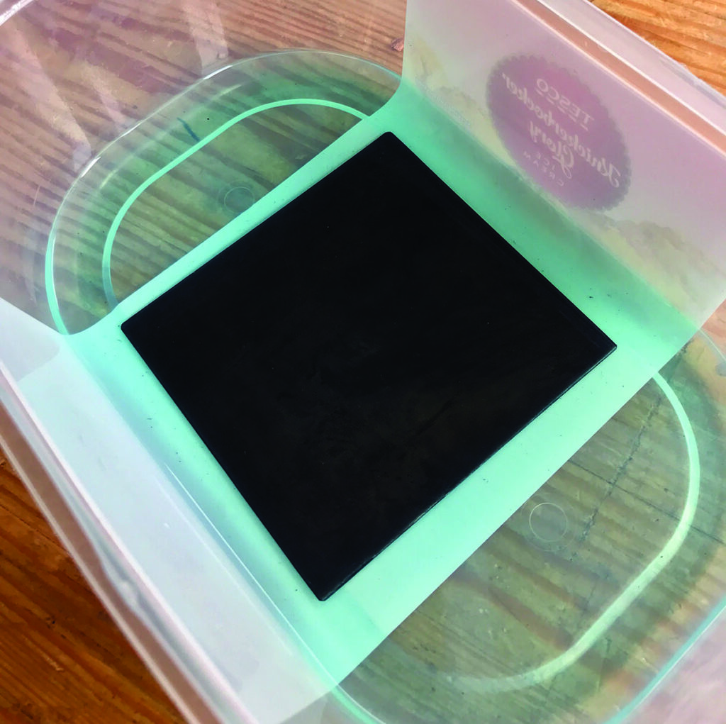 Black square submerged in transparent container with liquid.