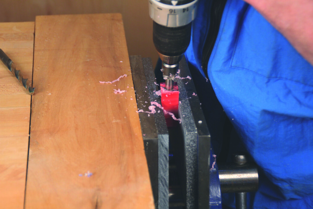 Drilling into plastic with power tool on workbench.
