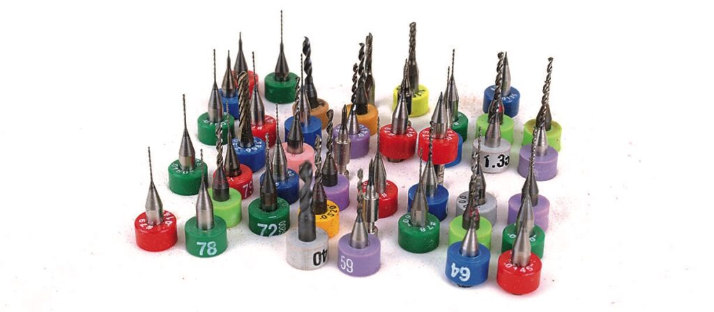Colourful drill bits arranged on white background.