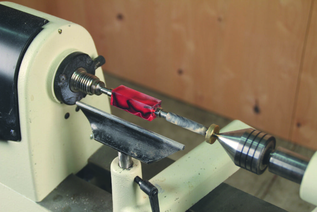 Wood lathe turning with red material block.