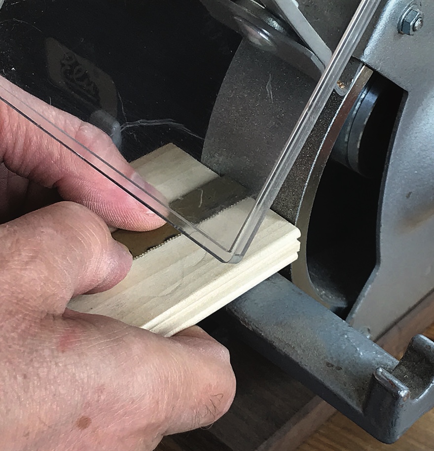 Wood being sanded on a belt sander machine.