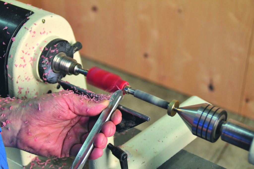 Woodturning on a lathe with carving tool.