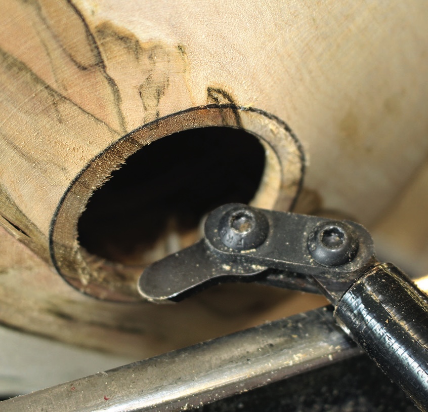 Woodworking tool carving a circular hole in wood.