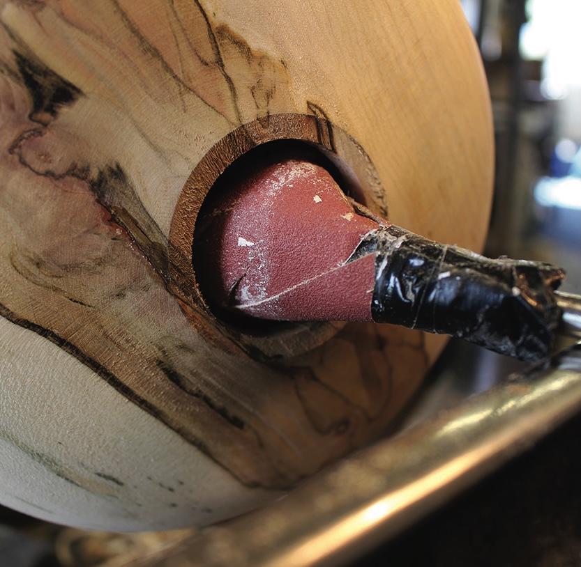 Wood being lathe-turned with attached paper abrasive.